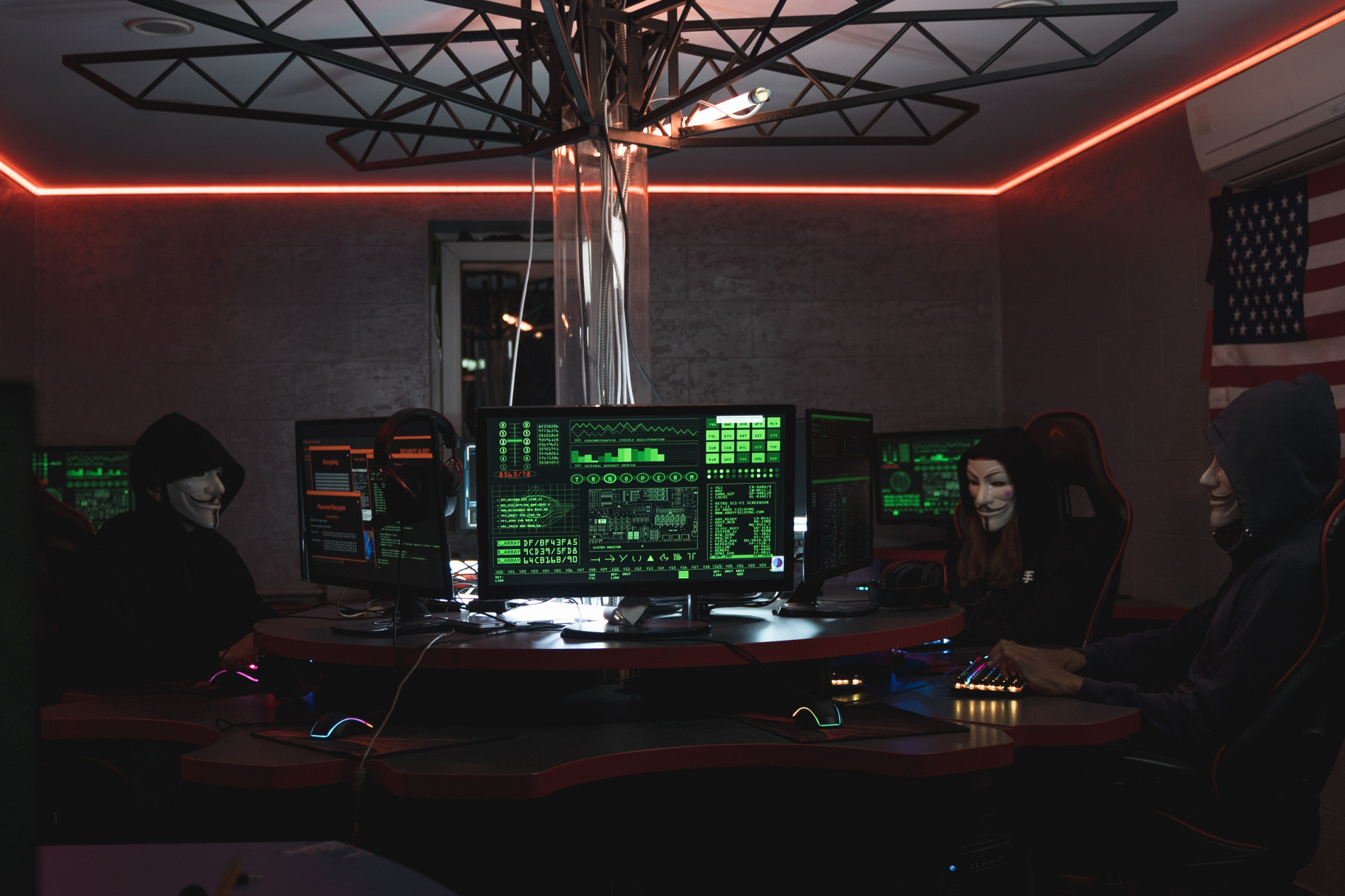 A group of anonymous hackers sitting around monitors and hacking representing something like a hacking group